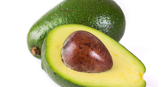 Aguacate abierto con su hueso sobre una tabla de madera