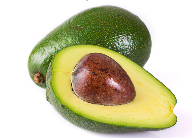 Aguacate abierto con su hueso sobre una tabla de madera
