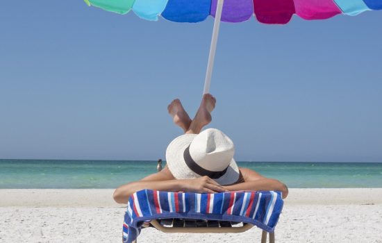 Mujer feliz caminando por la playa, ejemplo de estilo de vida saludable en verano.
