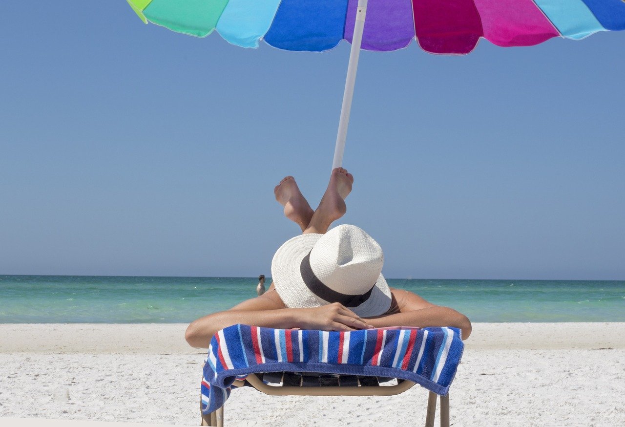 Mujer feliz caminando por la playa, ejemplo de estilo de vida saludable en verano.