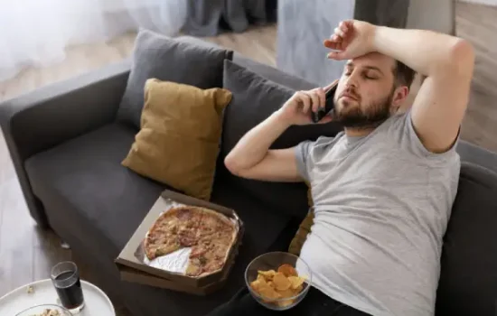 Hombre en el sofá con comida basura, vida sedentaria