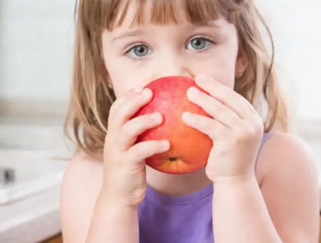 ni&ntilde;a peque&ntilde;a comiendo una manzana simbolizando alimentaci&oacute;n saludable para ni&ntilde;os