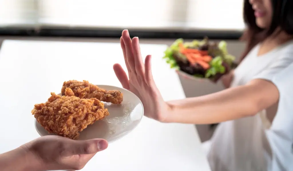 Mujer rechazando comida ultraprocesada mientras elige una opci&oacute;n saludable para mejorar la saciedad