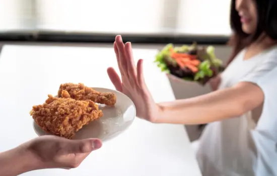Mujer rechazando comida ultraprocesada mientras elige una opci&oacute;n saludable para mejorar la saciedad