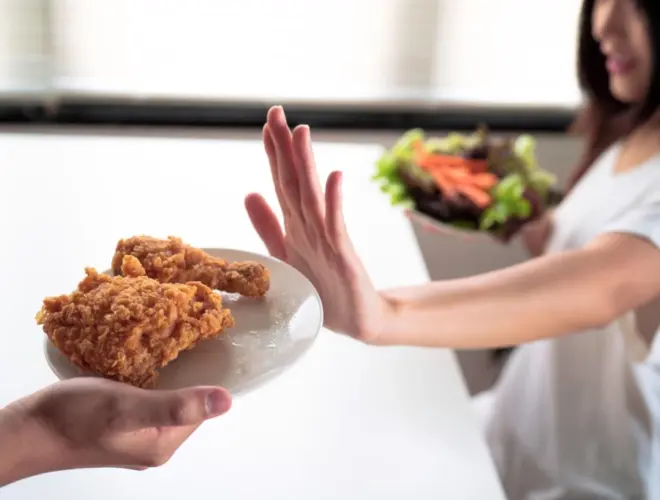 Mujer rechazando comida ultraprocesada mientras elige una opci&oacute;n saludable para mejorar la saciedad