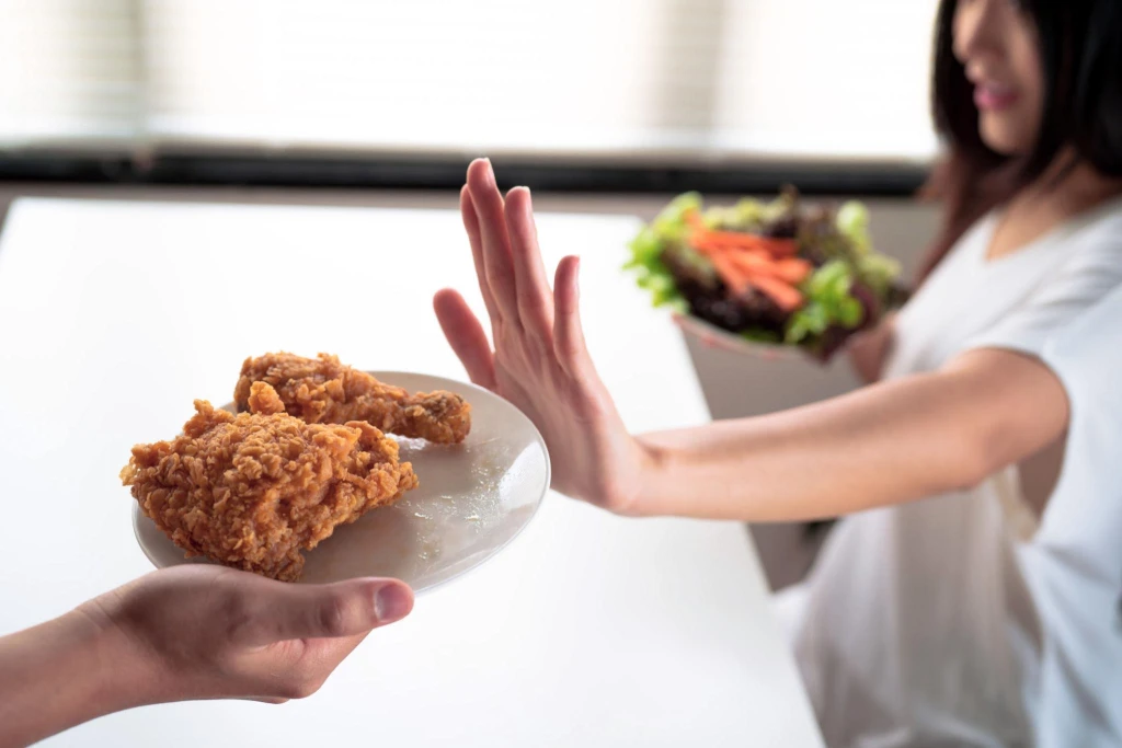 Mujer rechazando comida ultraprocesada mientras elige una opci&oacute;n saludable para mejorar la saciedad