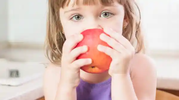 niña pequeña comiendo una manzana simbolizando alimentación saludable para niños