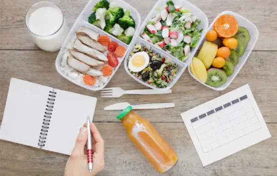 Planificaci&oacute;n semanal de meal prep con t&aacute;peres de pescado, verduras, fruta, huevo y vaso de leche