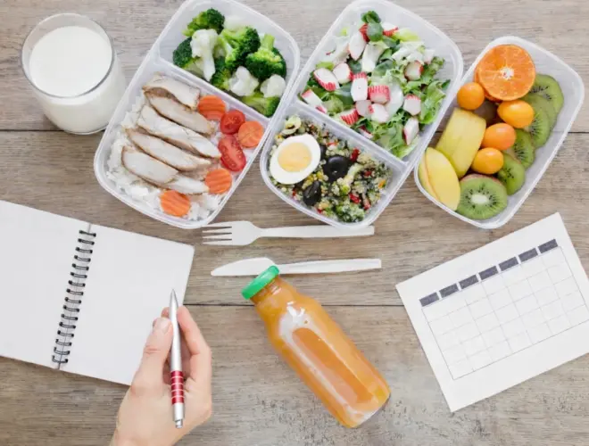 Planificación semanal de meal prep con táperes de pescado, verduras, fruta, huevo y vaso de leche