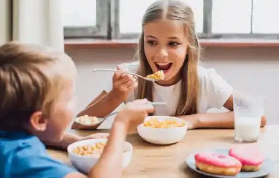 Alimentos que debes eliminar de la dieta de tu hijo: ultraprocesados comunes en una mesa (cereales azucarados, refresco, bollería, snacks)