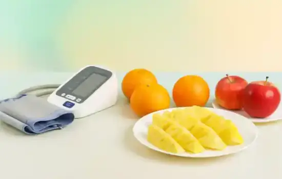Alimentación para la diabetes con medidor de tensión y frutas (naranja, piña y manzana) sobre mesa blanca