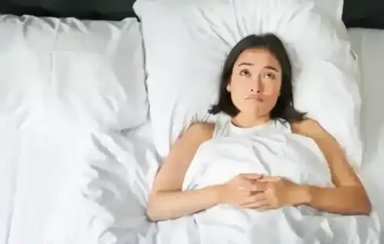 Persona cenando tarde con un plato en una mesa de noche, asociado a insomnio y aumento de peso