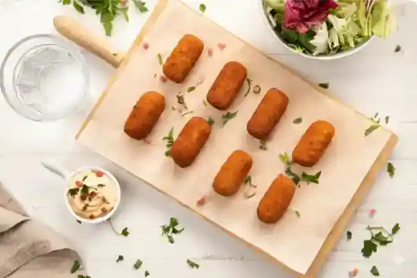 Tuppers con comida de aprovechamiento etiquetados y restos de verduras listos para hacer caldo en una cocina