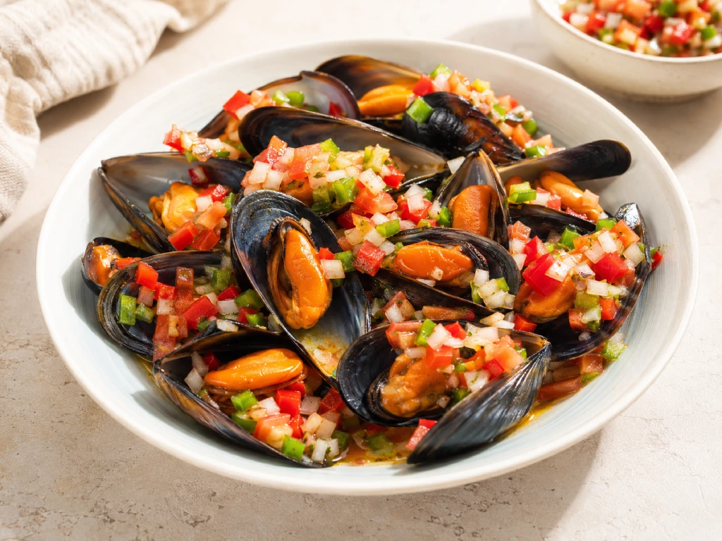 Mejillones con pipirrana servidos en plato blanco con dados de verdura y ali&ntilde;o suave, foto luminosa y realista