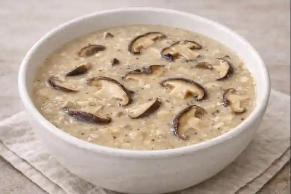 Salsa de setas shiitake cremosa servida en cuenco blanco, con l&aacute;minas de shiitake visibles y acabado suave, en fotograf&iacute;a muy luminosa sobre fondo neutro.