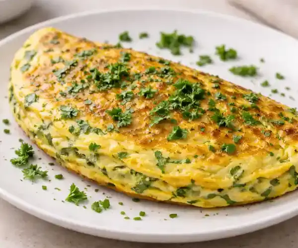 Tortilla a las finas hierbas esponjosa y dorada en plato blanco, con perejil y cebollino frescos, fotografía luminosa estilo gourmet.
