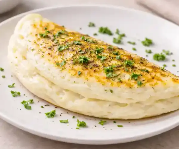 Tortilla de claras esponjosa y ligera en plato blanco, textura suave y dorado uniforme, fotografía luminosa estilo gourmet.