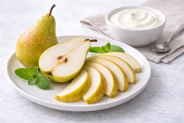 Dos piezas de fruta troceada de temporada servidas en bol con yogur desnatado 0% aparte, en una presentación luminosa.