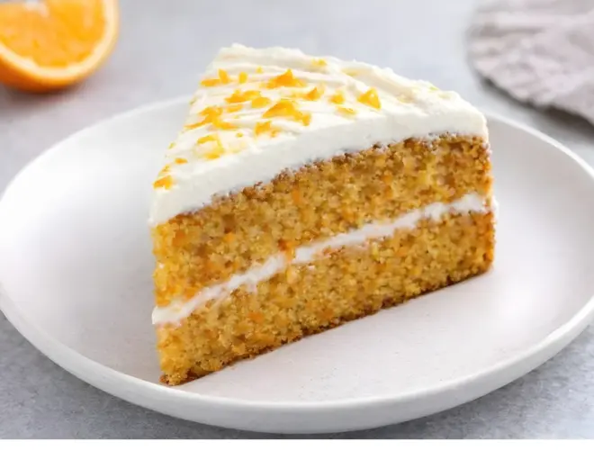 Tarta de zanahoria y naranja con miga jugosa y acabado dorado, servida en plato blanco con luz natural y fondo neutro.