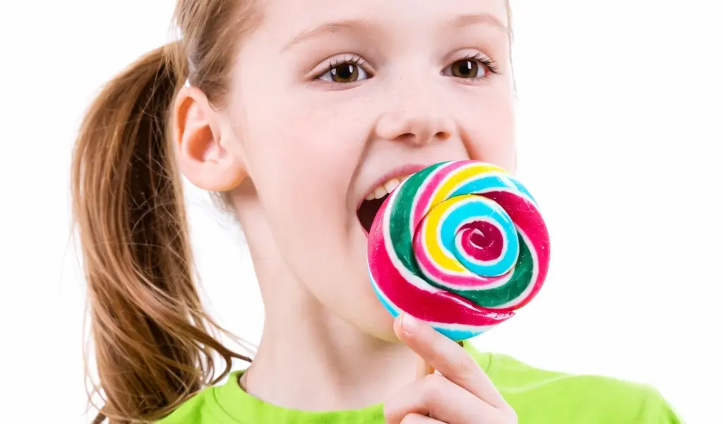 calor&iacute;as de las golosinas en una ni&ntilde;a comiendo piruleta de colores