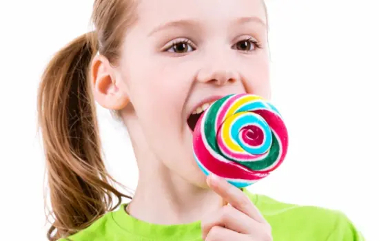 calorías de las golosinas en una niña comiendo piruleta de colores