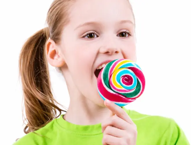 calor&iacute;as de las golosinas en una ni&ntilde;a comiendo piruleta de colores