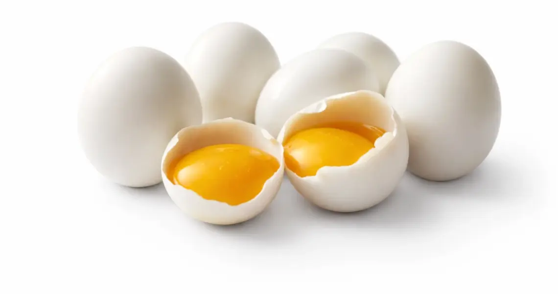 Huevos crudos con yema visible abiertos sobre fondo blanco