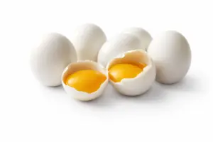 cuantos-huevos-se-pueden-comer-al-dia-la-ciencia-responde Huevos crudos con yema visible abiertos sobre fondo blanco