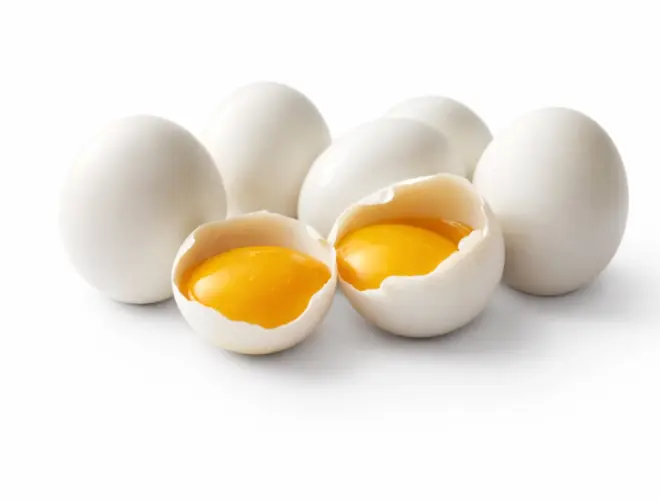 Huevos crudos con yema visible abiertos sobre fondo blanco