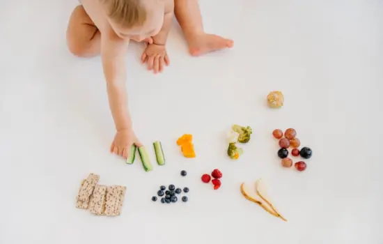 Bebé comiendo alimentos saludables como frutas, verduras y cereales en una alimentación infantil equilibrada