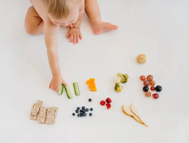 Beb&eacute; comiendo alimentos saludables como frutas, verduras y cereales en una alimentaci&oacute;n infantil equilibrada