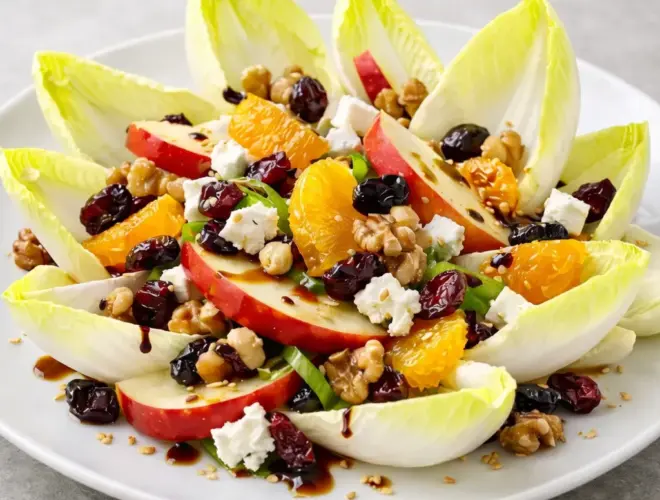 Ensalada agridulce de endivia: hojas de endivia crujientes con manzana, naranja, frutos secos y vinagreta suave en plato blanco, fotograf&iacute;a luminosa y realista
