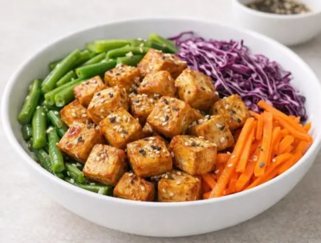 Ensalada de tofu marinado con jud&iacute;as verdes, zanahoria y col lombarda, servida en bol blanco y acabada con semillas de s&eacute;samo