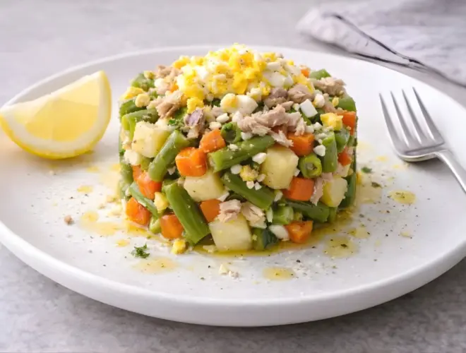 Ensaladilla de jud&iacute;as verdes en plato llano con patata y zanahoria, at&uacute;n desmenuzado y huevo duro en rodajas, ali&ntilde;ada con lim&oacute;n y aceite de oliva, luz natural y fondo neutro