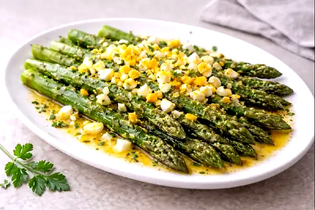 Esp&aacute;rragos trigueros con huevo duro picado y aceite de oliva con ajo, servidos en fuente blanca con luz natural y fondo neutro