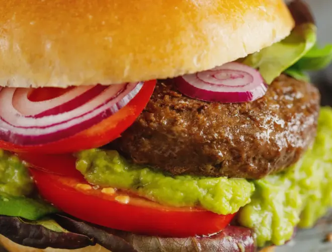 Hamburguesas de soja caseras servidas en pan integral con lechuga, tomate y cebolla morada, en fondo neutro y luz natural