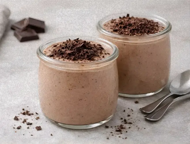 Mouse light de chocolate servido en tarros de cristal, con virutas de chocolate negro por encima, fotografía luminosa sobre fondo neutro