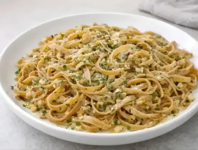 Pasta integral con ajo y especias salteada con ajo picado, aceite de oliva y queso rallado, servida en plato blanco con luz natural.