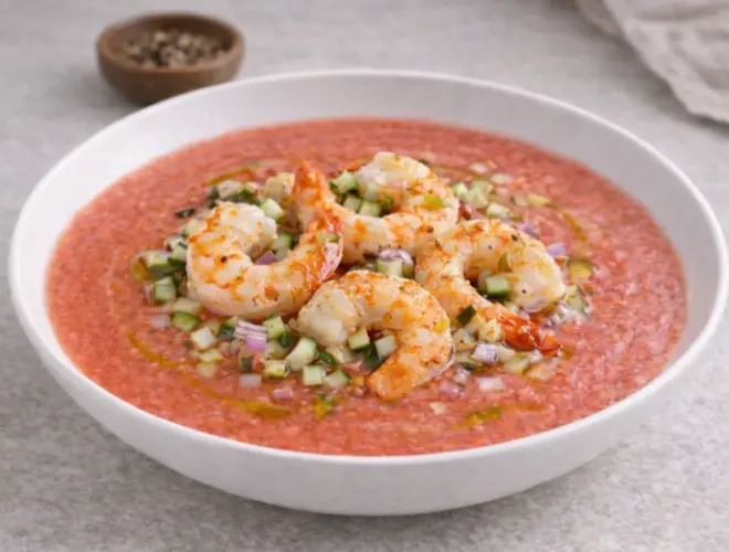 Salmorejo de sand&iacute;a y langostinos en plato blanco, con langostinos a la plancha y un hilo de aceite de oliva, foto gourmet luminosa sobre fondo neutro.