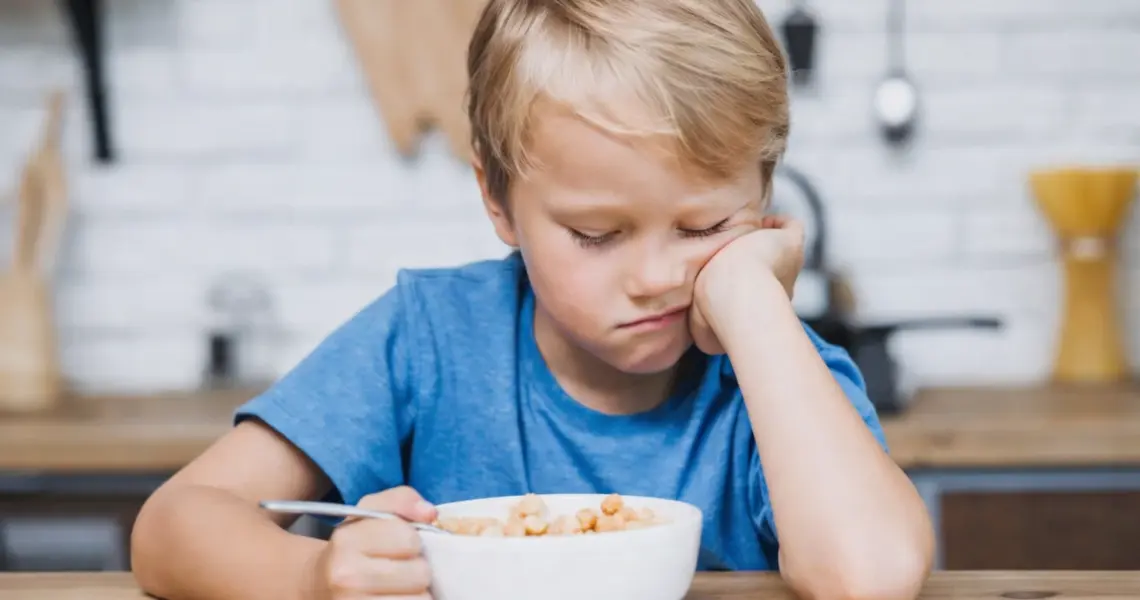 Ni&ntilde;o peque&ntilde;o mostrando rechazo a la comida sentado frente a un bol durante la hora de comer
