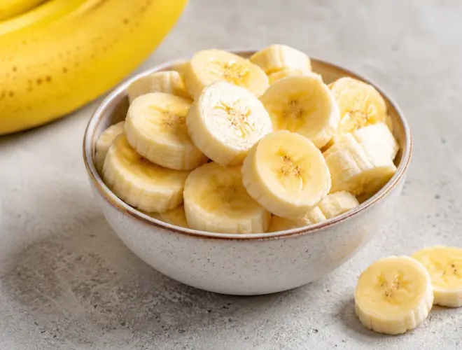 Banana cortada en rodajas servida en un bol claro sobre fondo neutro, con luz natural y estilo gourmet saludable.