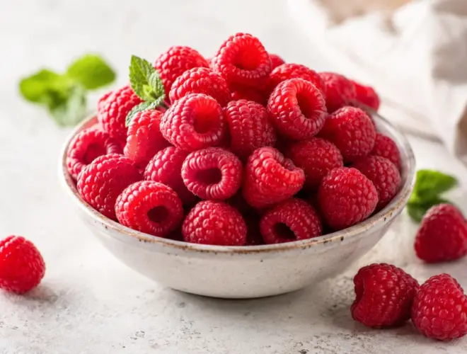 Frambuesas frescas servidas en un bol claro sobre fondo neutro, con luz natural y estilo gourmet saludable.